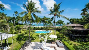 A resort with a swimming pool, lounge chairs, palm trees, and a view of the ocean. - Morabito Art Villa (Tibubeneng)