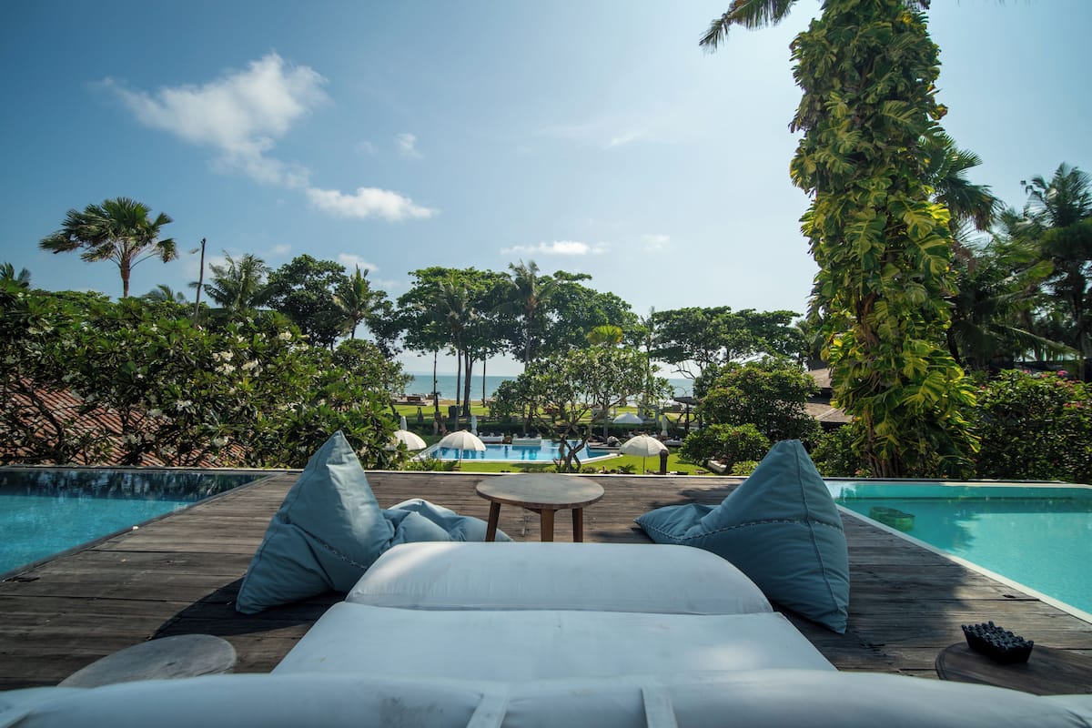 A wooden deck with a pool, lounge chairs, and umbrellas.