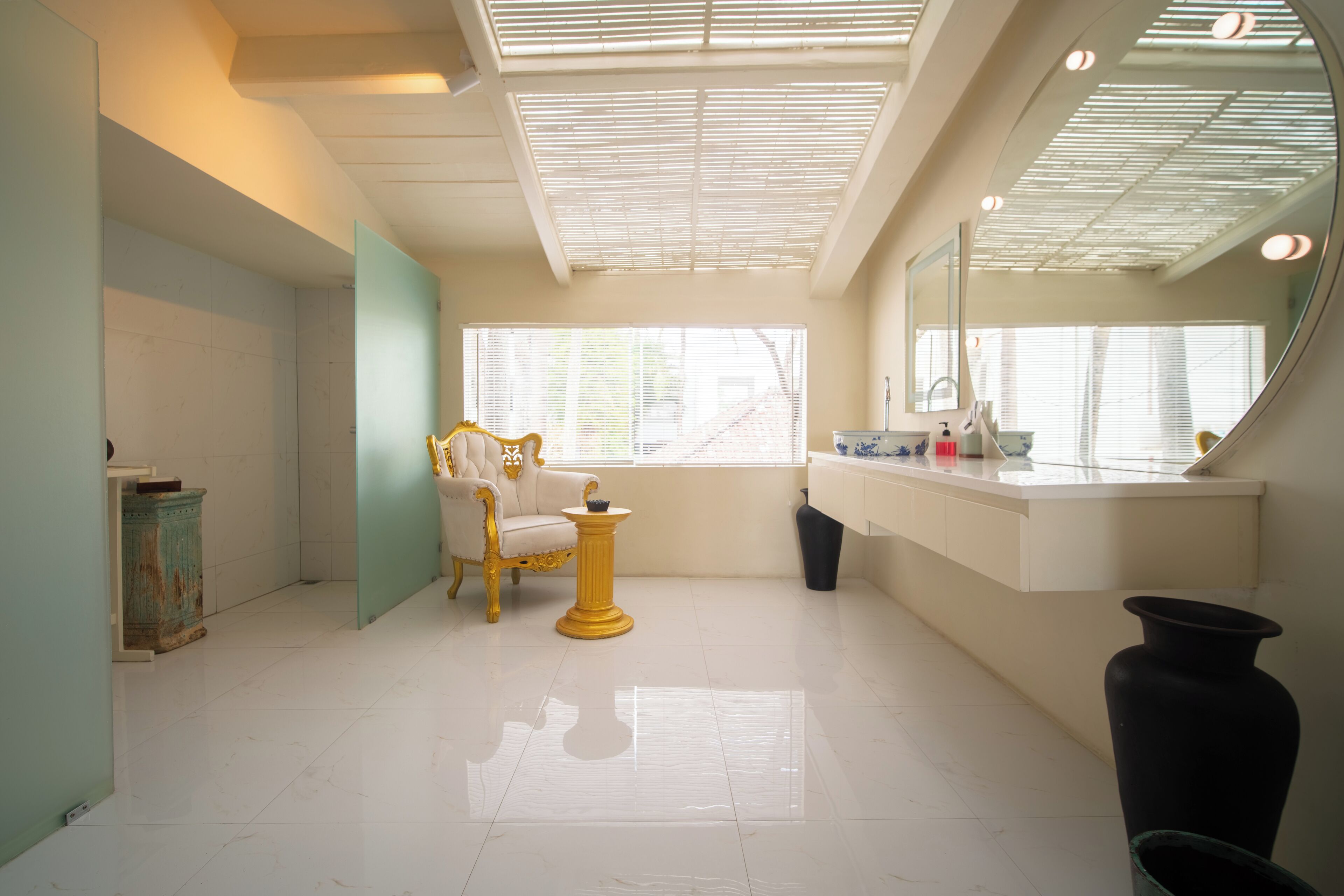 Un baño con tocador, espejo, silla y un amplio ventanal.