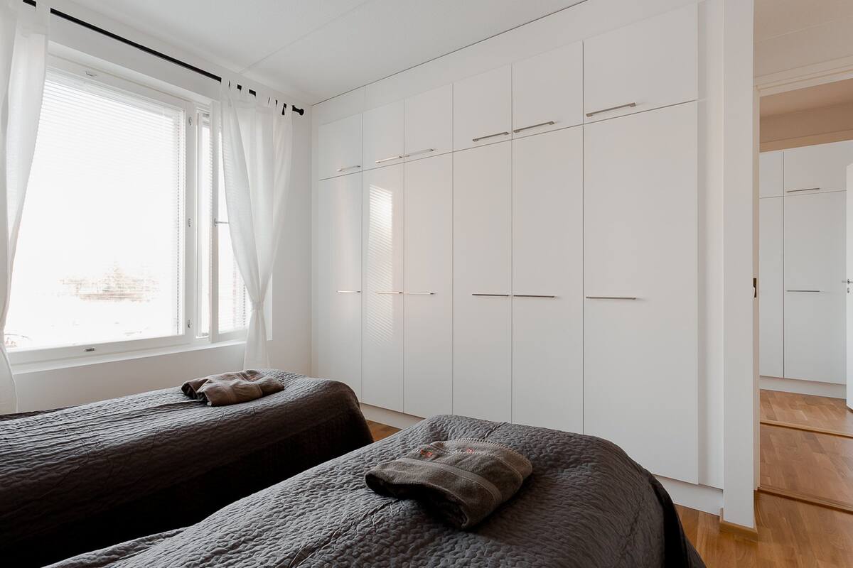 Ein Schlafzimmer mit zwei Betten, einem großen Kleiderschrank und einem Fenster mit Vorhängen.