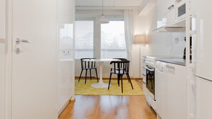 A modern kitchen with white cabinets, a white stove, and a yellow patterned rug. - Forenom Apts Turku Laukkavuori (Turku)