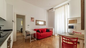 A modern kitchen with a dining area, a red sofa, and a white table. - Piazza Vittorio Luxury House (Roma)