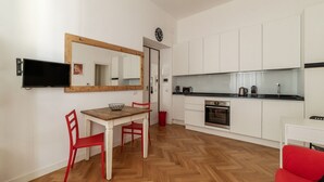 A modern kitchen with white cabinets, a wooden dining table, and red chairs. - Piazza Vittorio Luxury House (Roma)