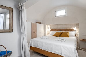 A bedroom with a bed, a wardrobe, a window, and a mirror.