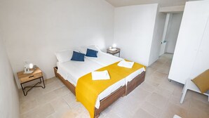 Een slaapkamer met een bed, nachtkastjes, een kledingkast en een deur naar een andere kamer.