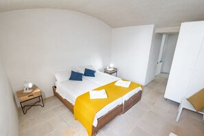 Un dormitorio con cama, mesitas de noche, un armario y una puerta que da a otra habitación.