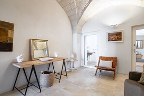 Ein Zimmer mit Holztisch, Spiegel, Korbsessel und einer Couch.