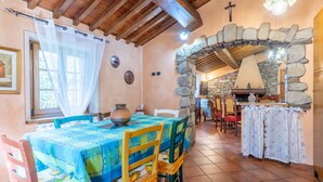 A dining area with a stone archway, wooden ceiling beams, and a table set with a blue tablecloth. - GuestHost - Wonderful 140 sqm apartment, perfect for 7 people, located on the first floor of an old renovated semi-detached house surrounded by greenery (stairs to access it).The apartment is located in Borgo a Mozzano, a picturesque village immersed in  (Borgo a Mozzano)