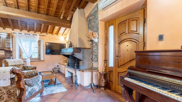 A living room with a fireplace, a piano, and a stone wall. - GuestHost - Wonderful 140 sqm apartment, perfect for 7 people, located on the first floor of an old renovated semi-detached house surrounded by greenery (stairs to access it).The apartment is located in Borgo a Mozzano, a picturesque village immersed in  (Borgo a Mozzano)