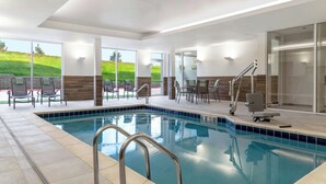 An indoor swimming pool with a clear view of the outdoors, including a grassy hill. - Fairfield by Marriott Inn & Suites Kansas City at The Legends (Kansas City)