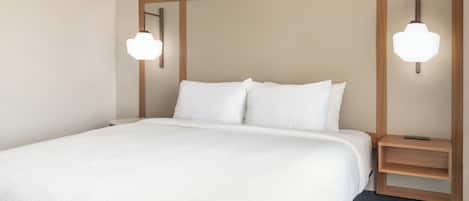 Una cama bien hecha con sábanas blancas, un cabecero de madera y dos mesitas de noche con lámparas.