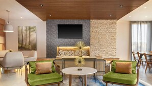 A modern living room with a sofa set, a coffee table, and a flat-screen TV mounted on a stone wall. - Fairfield by Marriott Inn & Suites Kansas City at The Legends (Kansas City)