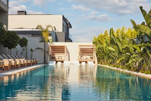 A swimming pool with lounge chairs and a building in the background.
