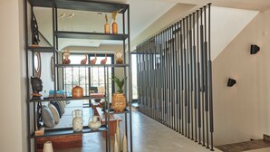 A modern interior with a black metal shelving unit displaying decorative items, a staircase with a black railing, and a view of the outdoors. - VENZI AYAYORGI ADULT ONLY +15 (Cesme)