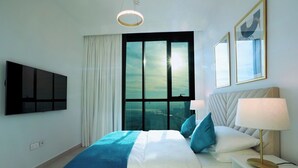 Ett modernt hotellrum med en stor säng, en platt-TV, ett fönster med utsikt över staden och ett nattduksbord med en lampa.