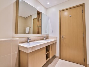 A modern bathroom with two sinks, a large mirror, and a wooden door.