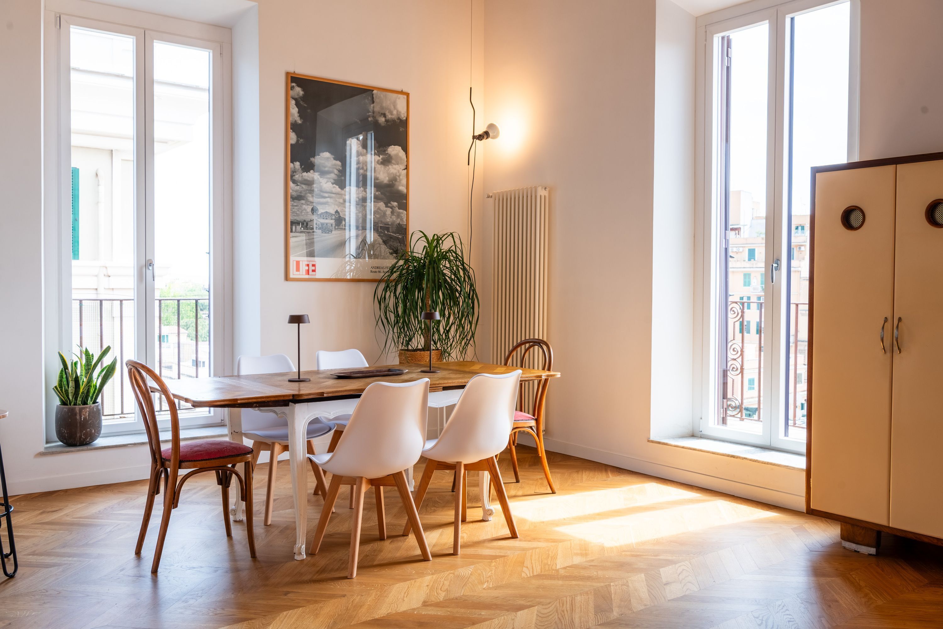 A dining area with a wooden table and chairs, a potted plant, and a radiator.