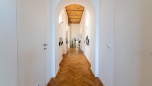 A hallway with a wooden herringbone floor, white walls, and an arched ceiling.