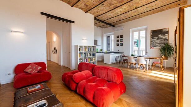 A spacious living area with a red sofa, a wooden coffee table, and a brick ceiling.