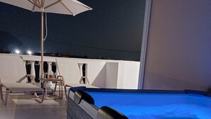 Un espace piscine aménagé sur le toit, avec un jacuzzi, des chaises longues et un parasol.