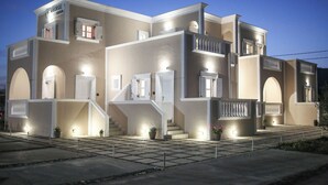Un immeuble à plusieurs étages doté d’une entrée imposante, de nombreux balcons et d’une façade bien éclairée.