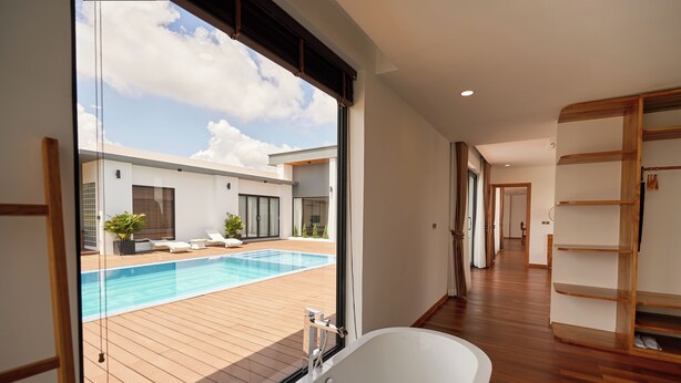 A modern hotel room with a large window overlooking a wooden deck and a swimming pool. - The Pine Mansion (Sen Monorom)