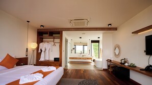 A modern hotel room with a large bed, a walk-in closet, a bathroom with a large window, and a desk with a mirror and a telephone. - The Pine Mansion (Sen Monorom)