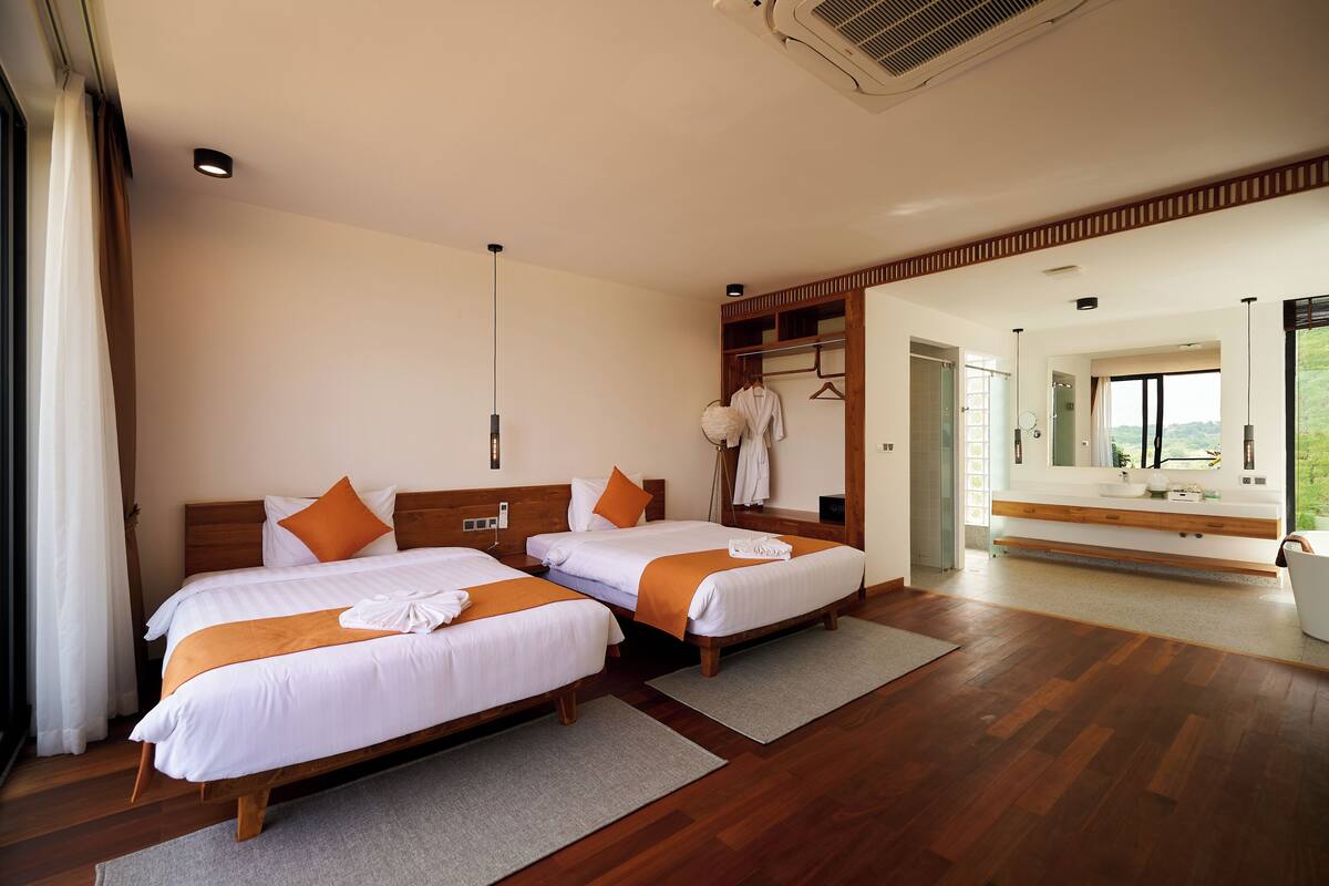 A hotel room with two beds, a large mirror, and a view of the outdoors.