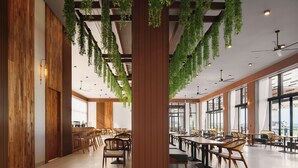 A spacious indoor dining area with wooden walls, hanging plants, and multiple dining tables and chairs. - The Pine Mansion (Sen Monorom)