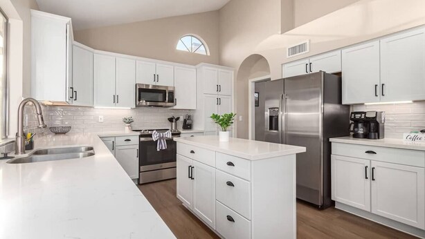 A modern kitchen with white cabinetry, stainless steel appliances, and a central island. - Solstice on Summit Retreat|Pool|Putt Grn|Sleeps 10 (Chandler)