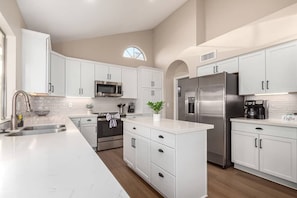 Una cocina moderna con armarios blancos, electrodomésticos de acero inoxidable y una isla central.