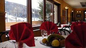 A dining table with red napkins, a fruit bowl, and wine glasses. - ALBA SPORTING HOTEL (Rocca di Mezzo)