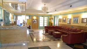 A lobby with a reception desk, a large leather sofa, and a staircase. - ALBA SPORTING HOTEL (Rocca di Mezzo)