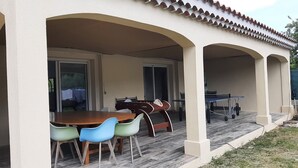 An outdoor patio with a table and chairs, a covered area with arches, and a view of the backyard. - Location Villa Avec 2 Appartements Ind, Proche du Lac de Ste Croix et du Verdon (Régusse)