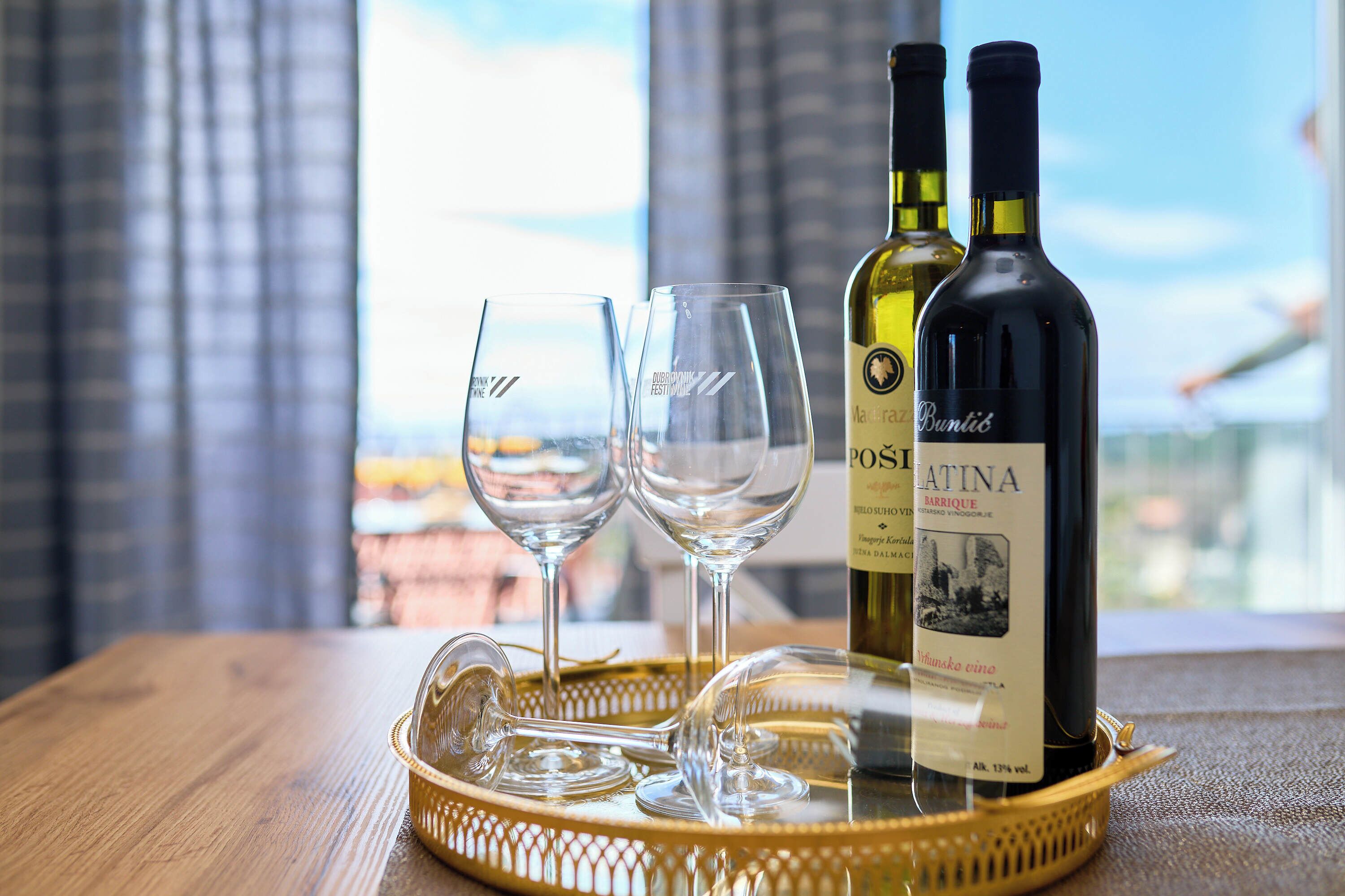 A tray with two wine bottles and two glasses on a wooden table.