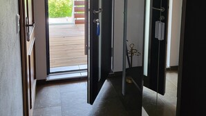 A hallway with a glass door leading to an outdoor area, a door with a towel rack, and a tiled floor. - Neu Renovierte Ferienwohnung, 50qm, mit Vollausgestatteter Küche (Eggstätt)
