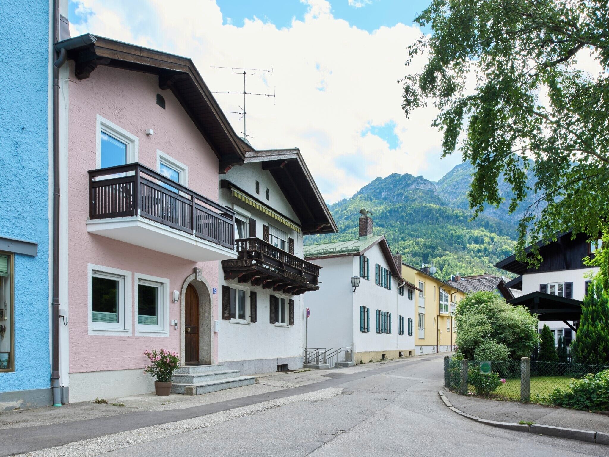 Reihenweise farbenfrohe Häuser mit Balkonen, eine Straße und eine gebirgige Kulisse.