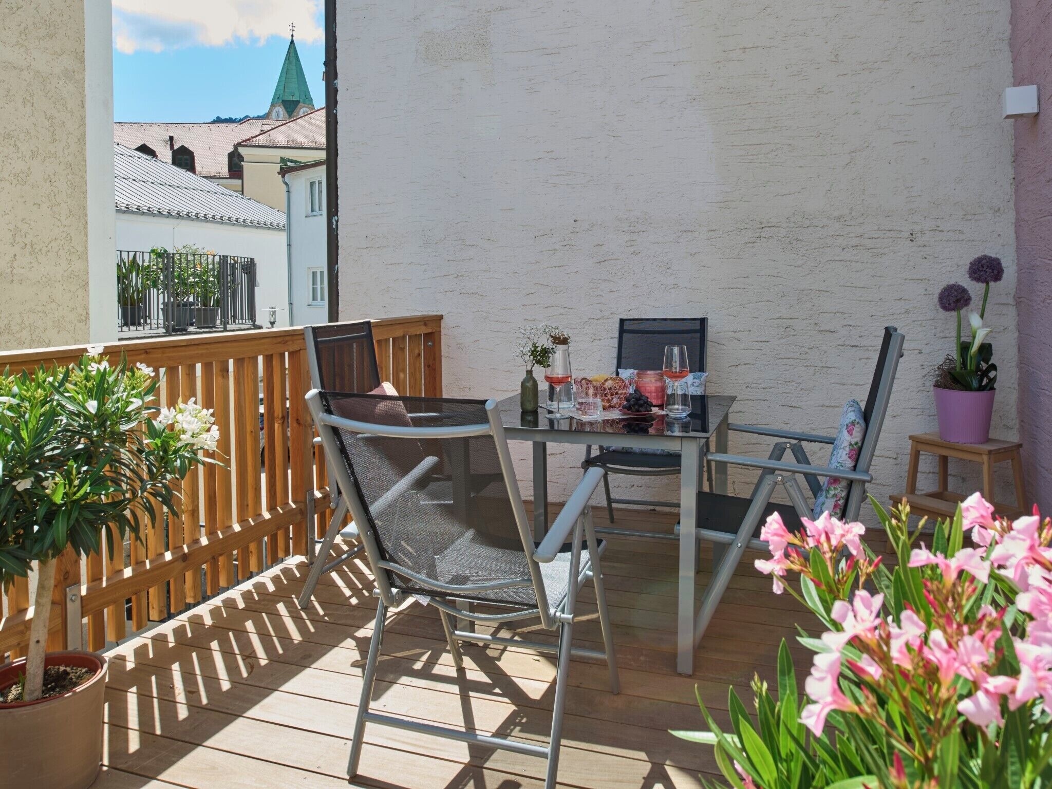 Un balcon avec une table, des chaises et des plantes en pot.