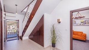 Un escalier avec des rampes en bois, offrant une vue sur le paysage urbain à travers une porte ouverte.