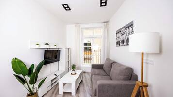 A modern living room with a white TV stand, a grey sofa, a coffee table, and a floor lamp.
