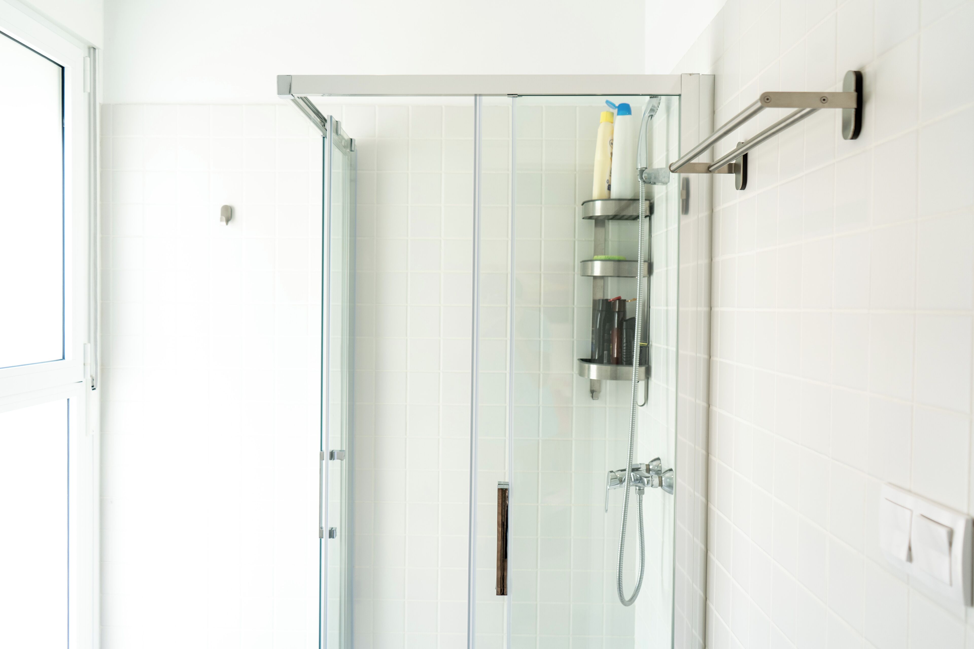 A modern bathroom with a glass-enclosed shower, a handheld showerhead, and a wall-mounted faucet.