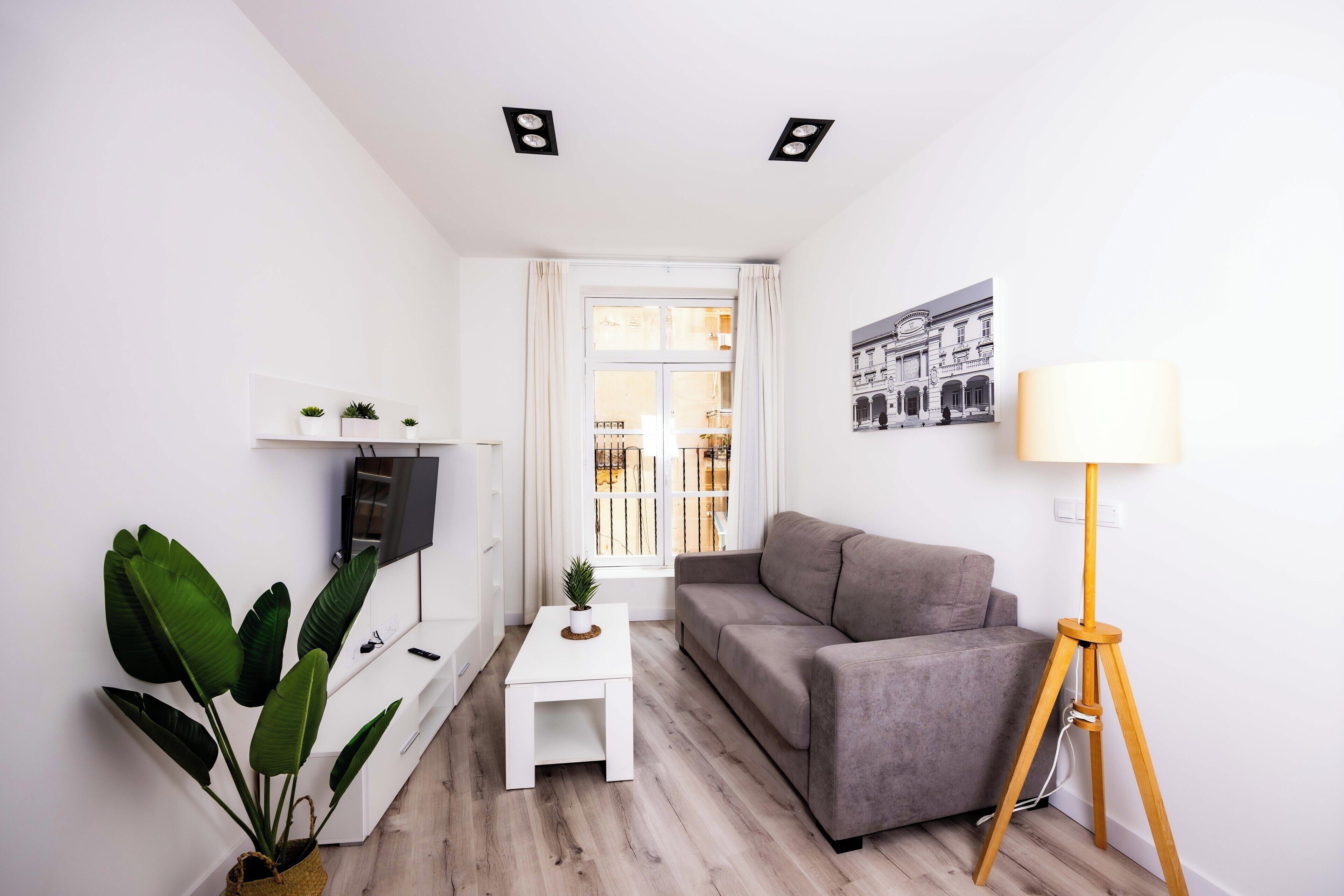 A modern living room with a sofa, a coffee table, a TV, and a floor lamp.