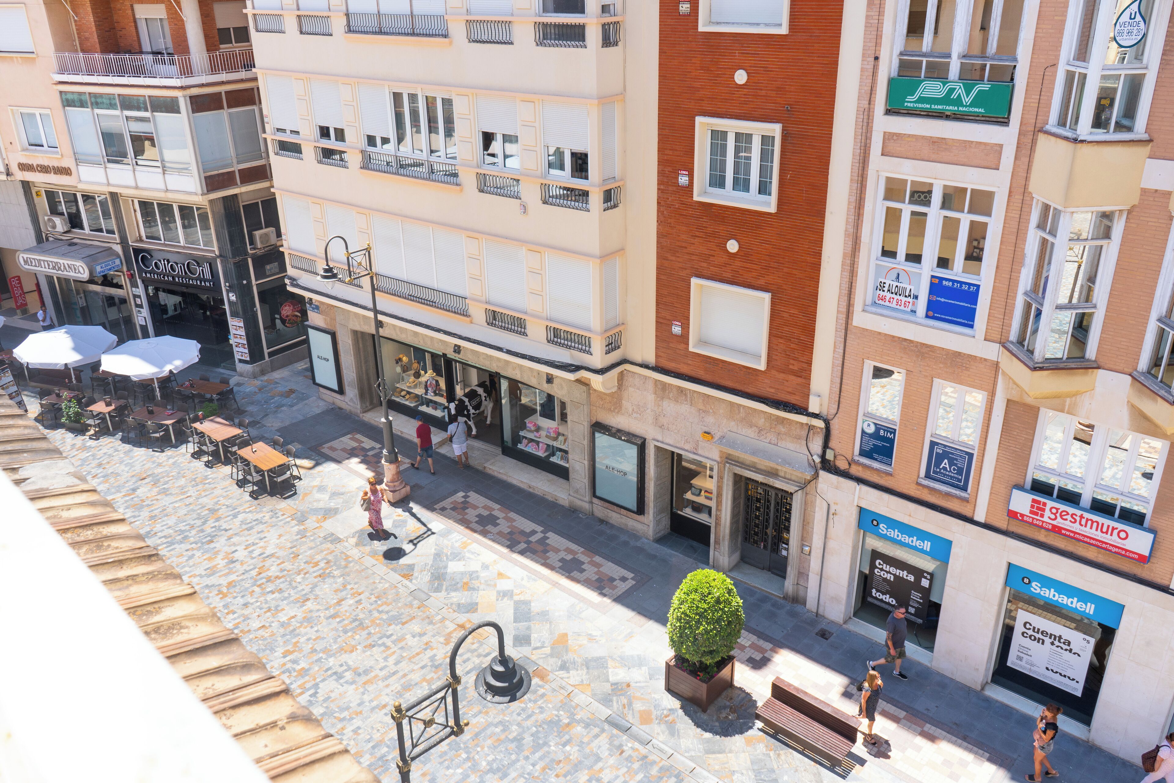 A multi-story building with various shops on the ground floor, including a restaurant and a bank.