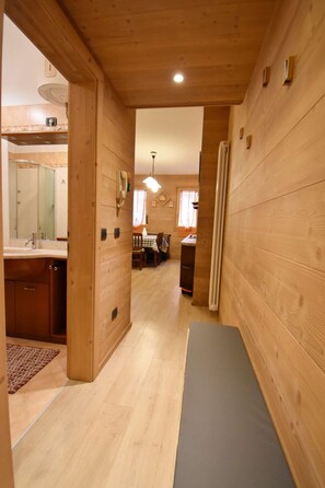 A wooden interior with a kitchen area, a dining table, and a bench. - Nambino On The Slopes (Madonna di Campiglio)