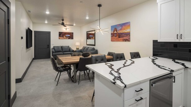 A modern kitchen with white cabinets, a marble countertop, and a built-in dishwasher. - Vizcaya #7 - Moab's Newest Luxury Rental (Moab)