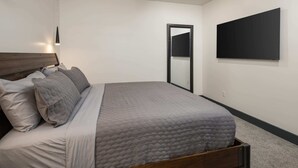 A bedroom with a bed, a ceiling fan, a wall-mounted TV, and a door. - Vizcaya #7 - Moab's Newest Luxury Rental (Moab)