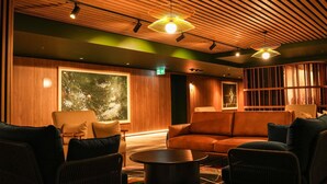 A modern lounge with wooden paneling, leather sofas, and a large window. - Peppers Gladstone (Barney Point)