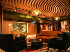 Un salón moderno con paneles de madera, sofás de cuero y un amplio ventanal.