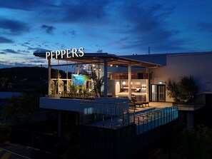Un edificio moderno con fachada de vidrio, piscina y zona de bar.