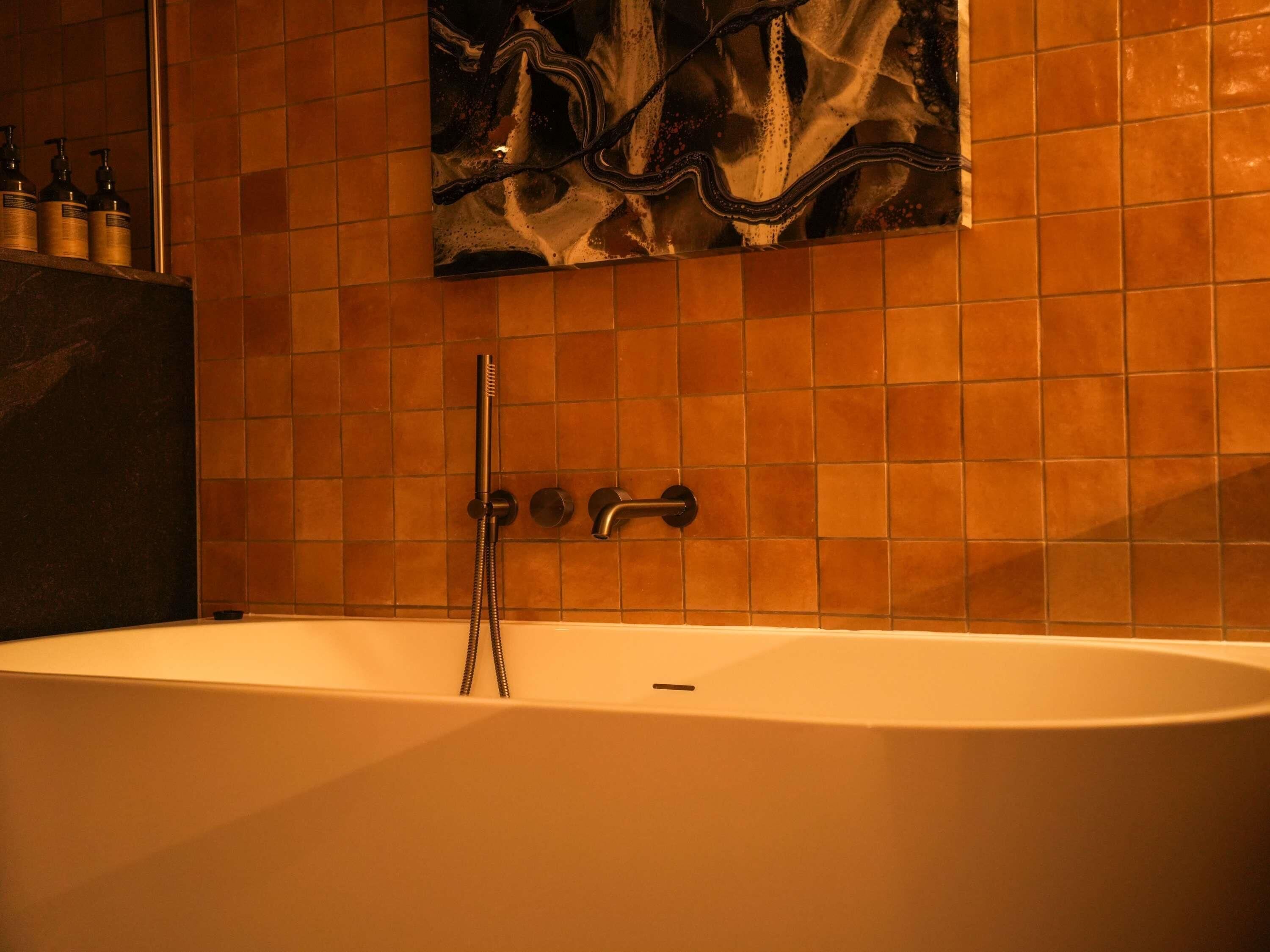 A bathroom with a bathtub, a shower, and a tiled wall.